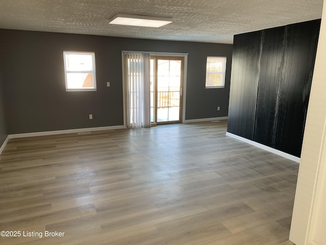 spare room with a healthy amount of sunlight, a textured ceiling, and wood finished floors