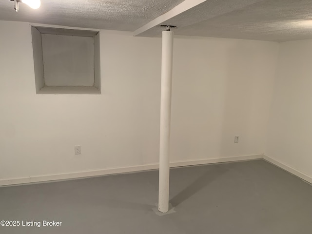 finished basement featuring a textured ceiling and baseboards