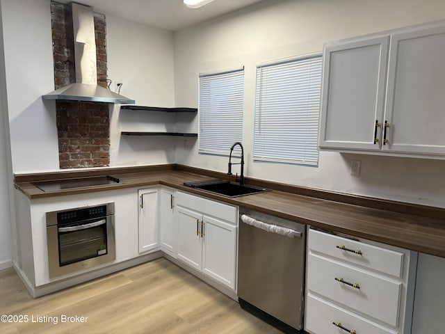 kitchen featuring wall chimney exhaust hood, wood counters, stainless steel appliances, open shelves, and a sink