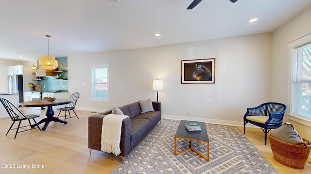 living room featuring baseboards, ceiling fan, light wood-style flooring, and recessed lighting