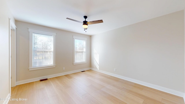 empty room featuring ceiling fan, light wood finished floors, and baseboards