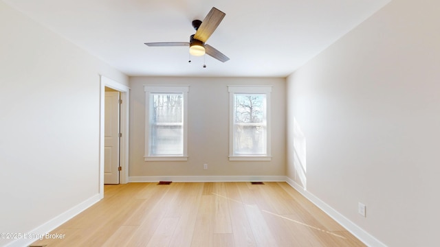 empty room with ceiling fan, visible vents, light wood-style flooring, and baseboards