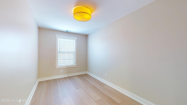 spare room with light wood finished floors, visible vents, and baseboards