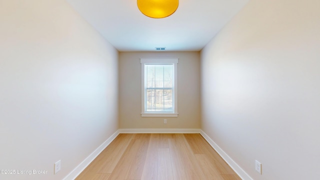 unfurnished room featuring light wood-style floors, visible vents, and baseboards