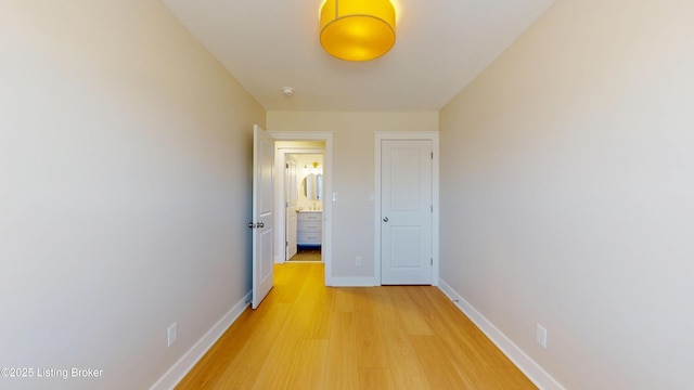 corridor with light wood-type flooring and baseboards