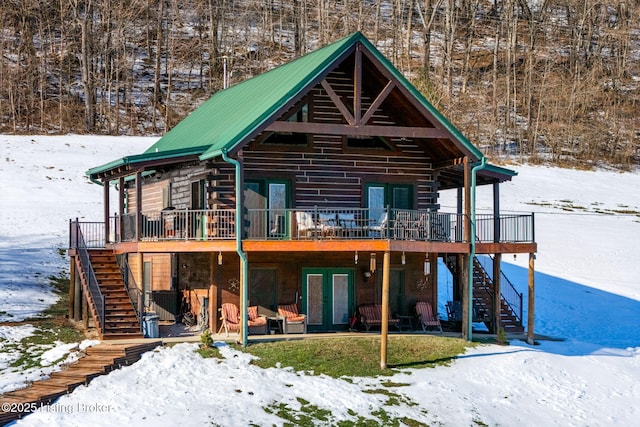 snow covered back of property featuring french doors and a wooden deck