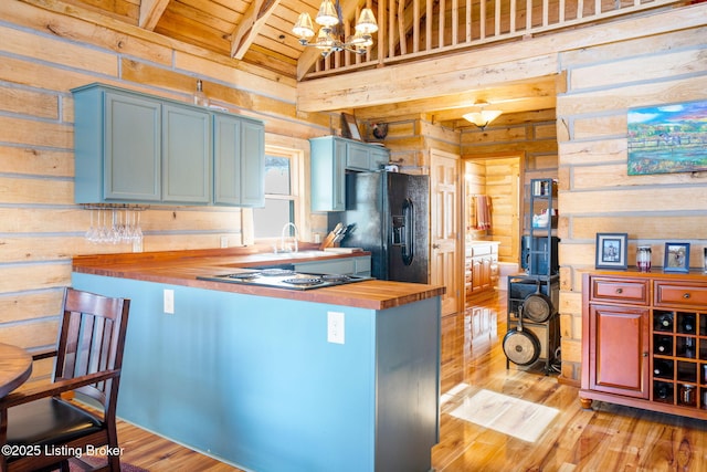 kitchen with wooden counters, wooden walls, light hardwood / wood-style flooring, and black appliances