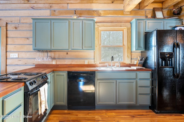 kitchen with light wood-type flooring, sink, wood counters, and black appliances