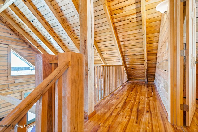 hallway with wood ceiling, lofted ceiling with beams, hardwood / wood-style floors, and wood walls