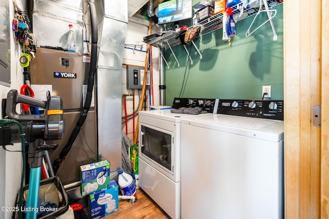 laundry room with washing machine and clothes dryer and light hardwood / wood-style flooring