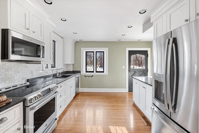 kitchen with white cabinetry, stainless steel appliances, and dark stone countertops