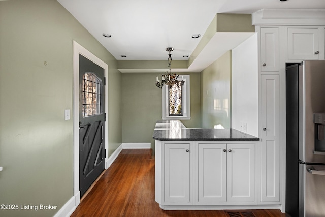 kitchen with white cabinetry, dark hardwood / wood-style flooring, hanging light fixtures, kitchen peninsula, and stainless steel refrigerator with ice dispenser