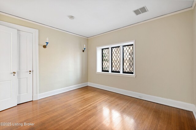 spare room featuring crown molding and hardwood / wood-style flooring