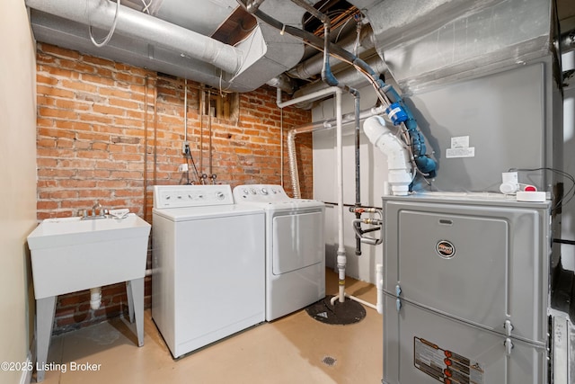 laundry room with heating unit, brick wall, and washer and dryer