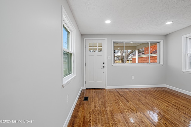 foyer entrance with wood-type flooring and a textured ceiling