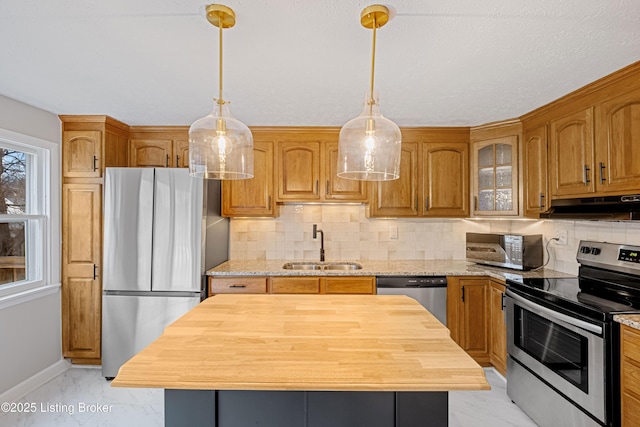 kitchen with stainless steel appliances, light stone countertops, sink, and a kitchen island