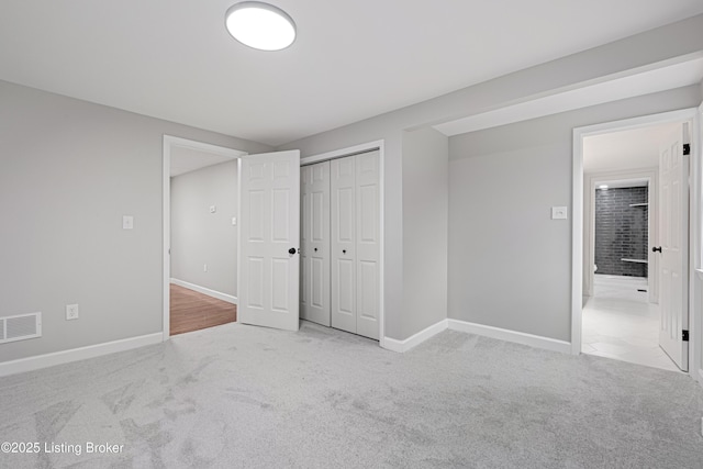 unfurnished bedroom with light colored carpet and a closet