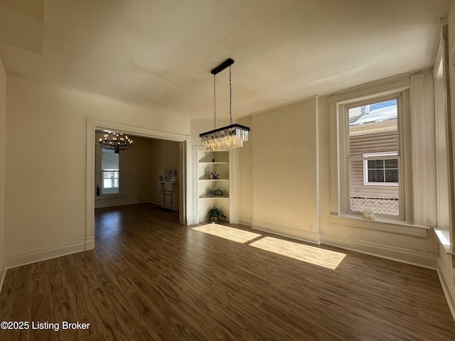 spare room featuring a chandelier and dark hardwood / wood-style flooring