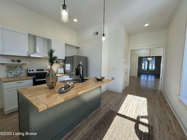 kitchen with wall chimney exhaust hood, pendant lighting, appliances with stainless steel finishes, and white cabinets