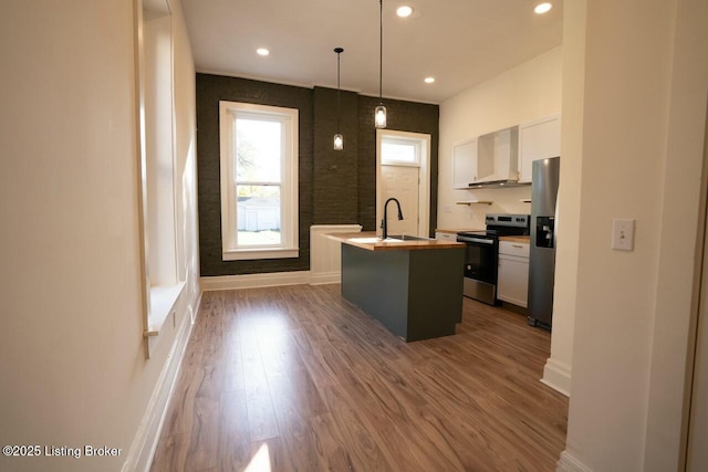 kitchen with appliances with stainless steel finishes, dark hardwood / wood-style floors, decorative light fixtures, white cabinets, and a kitchen island with sink