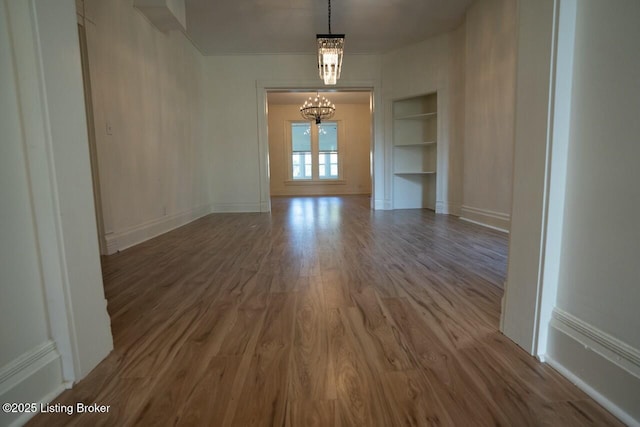 interior space featuring an inviting chandelier, wood-type flooring, and built in features