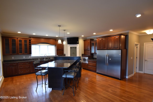 kitchen featuring a kitchen island, appliances with stainless steel finishes, a breakfast bar area, dark hardwood / wood-style flooring, and ornamental molding