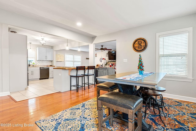 dining room with sink, ceiling fan, and light hardwood / wood-style flooring