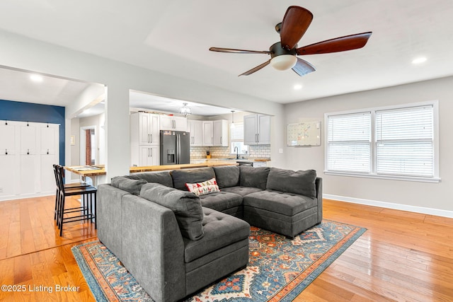 living room featuring sink, light hardwood / wood-style flooring, a healthy amount of sunlight, and ceiling fan