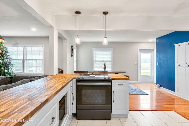 kitchen featuring pendant lighting, wood counters, white cabinetry, light tile patterned floors, and electric stove