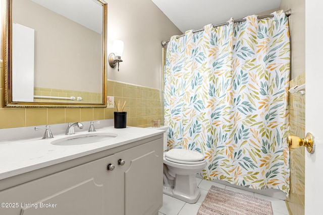 bathroom featuring tile patterned flooring, vanity, toilet, and tile walls