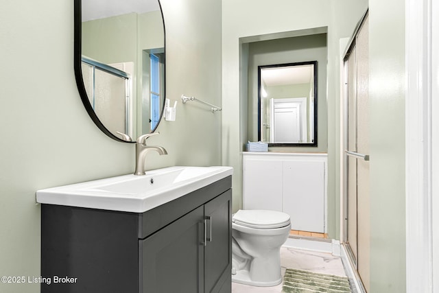 bathroom featuring vanity, toilet, and a shower with shower door