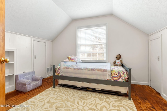 bedroom with hardwood / wood-style flooring, vaulted ceiling, and a textured ceiling