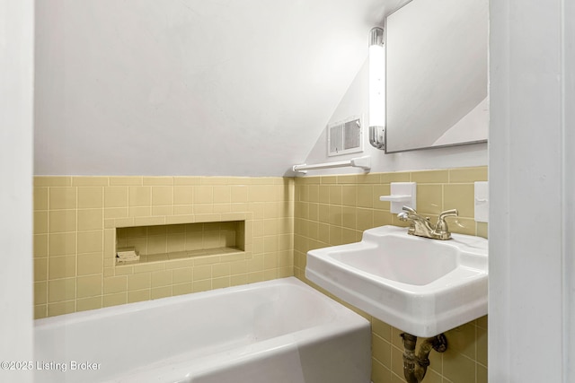 bathroom featuring tile walls, sink, and a washtub