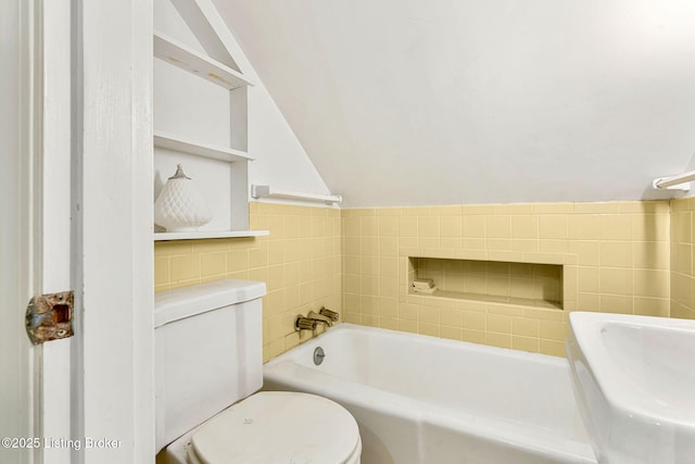 bathroom featuring tile walls, a tub, and toilet