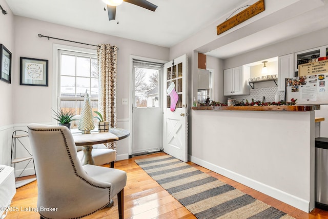 interior space featuring white cabinetry, white fridge, ceiling fan, kitchen peninsula, and light wood-type flooring