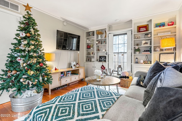 sitting room featuring ornamental molding, wood-type flooring, and built in shelves