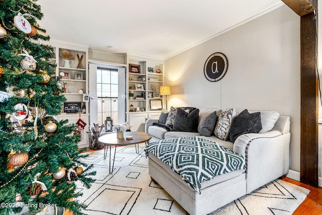 living room featuring ornamental molding, light hardwood / wood-style floors, and built in features