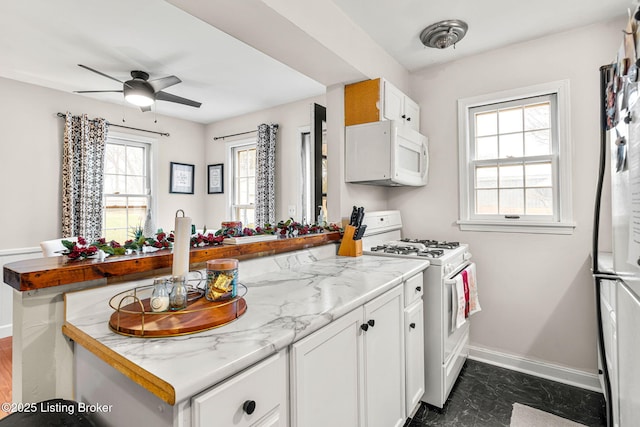 kitchen featuring a wealth of natural light, white cabinets, white appliances, and kitchen peninsula