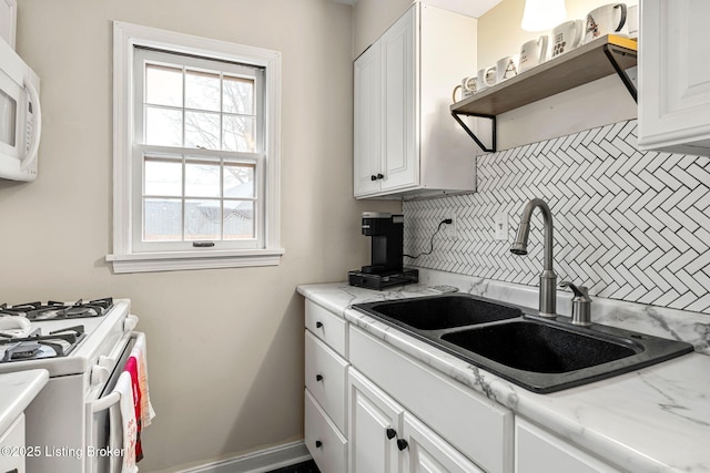 kitchen featuring sink, white cabinets, white appliances, light stone countertops, and backsplash