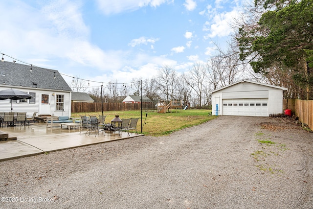 view of yard with a garage, a patio, an outdoor structure, and a playground