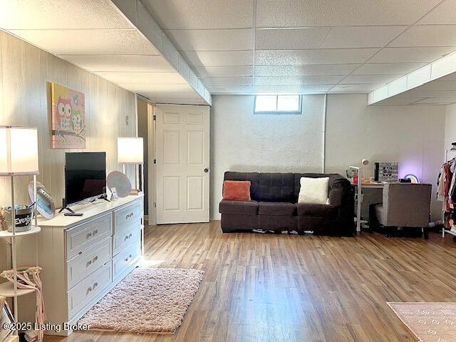 living room with a paneled ceiling and light hardwood / wood-style flooring