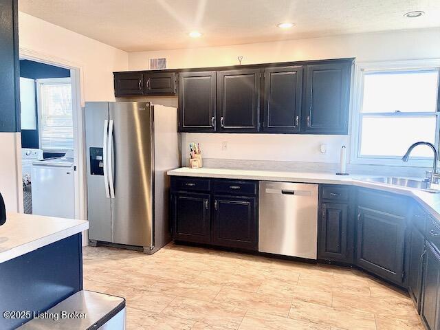 kitchen with washer and dryer, appliances with stainless steel finishes, and sink