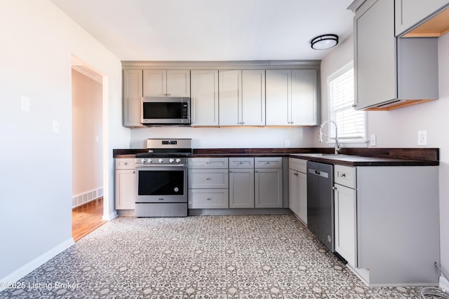 kitchen featuring appliances with stainless steel finishes, sink, and gray cabinetry