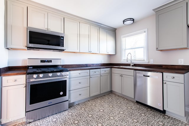 kitchen with appliances with stainless steel finishes, sink, and gray cabinetry