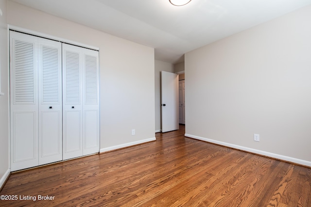 unfurnished bedroom with dark hardwood / wood-style flooring and a closet