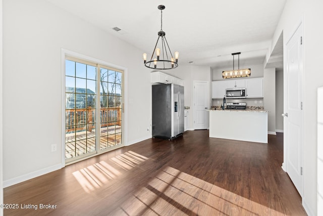 interior space featuring stainless steel appliances, light countertops, dark wood-type flooring, white cabinetry, and a chandelier