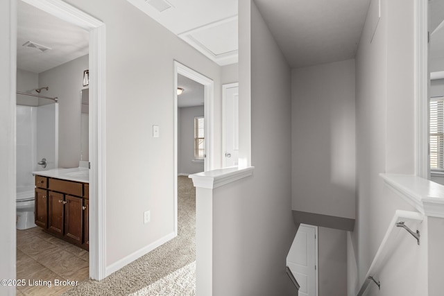 corridor with visible vents, light carpet, an upstairs landing, and baseboards