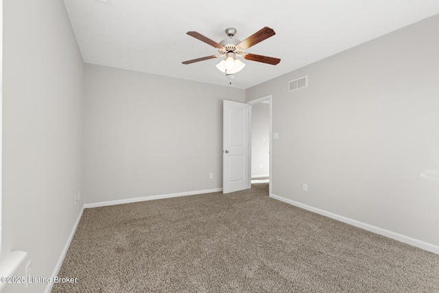 carpeted spare room with baseboards, visible vents, and a ceiling fan