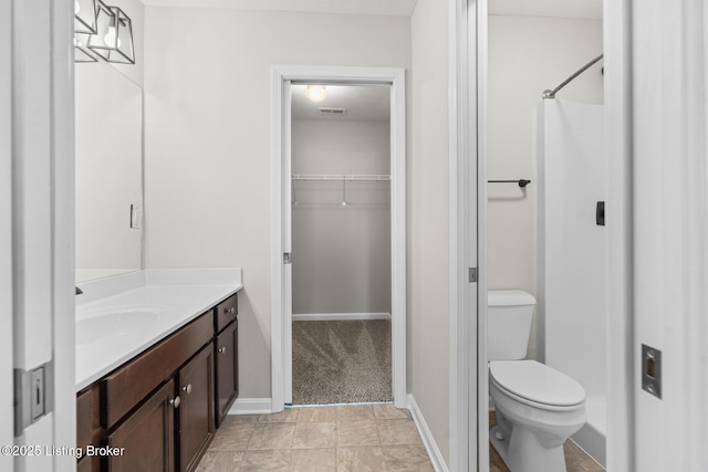 full bathroom featuring toilet, vanity, baseboards, a spacious closet, and a shower