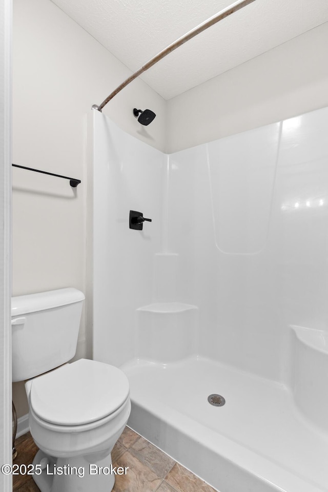 bathroom featuring walk in shower and toilet